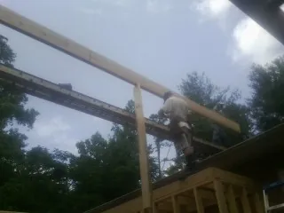 Carpenter setting a ridge beam over a new addition frame — Ice Dam Removal by Roofing Brothers in Springtown