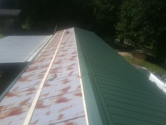Old rusted panels beside newly installed green metal roofing — Wind Damage Roof Repair by Roofing Brothers in Springtown