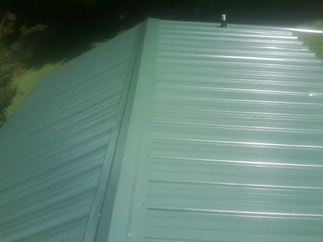 New green metal panels meeting at the ridge of a roof — Flat Roof Repair work by our crew in Springtown