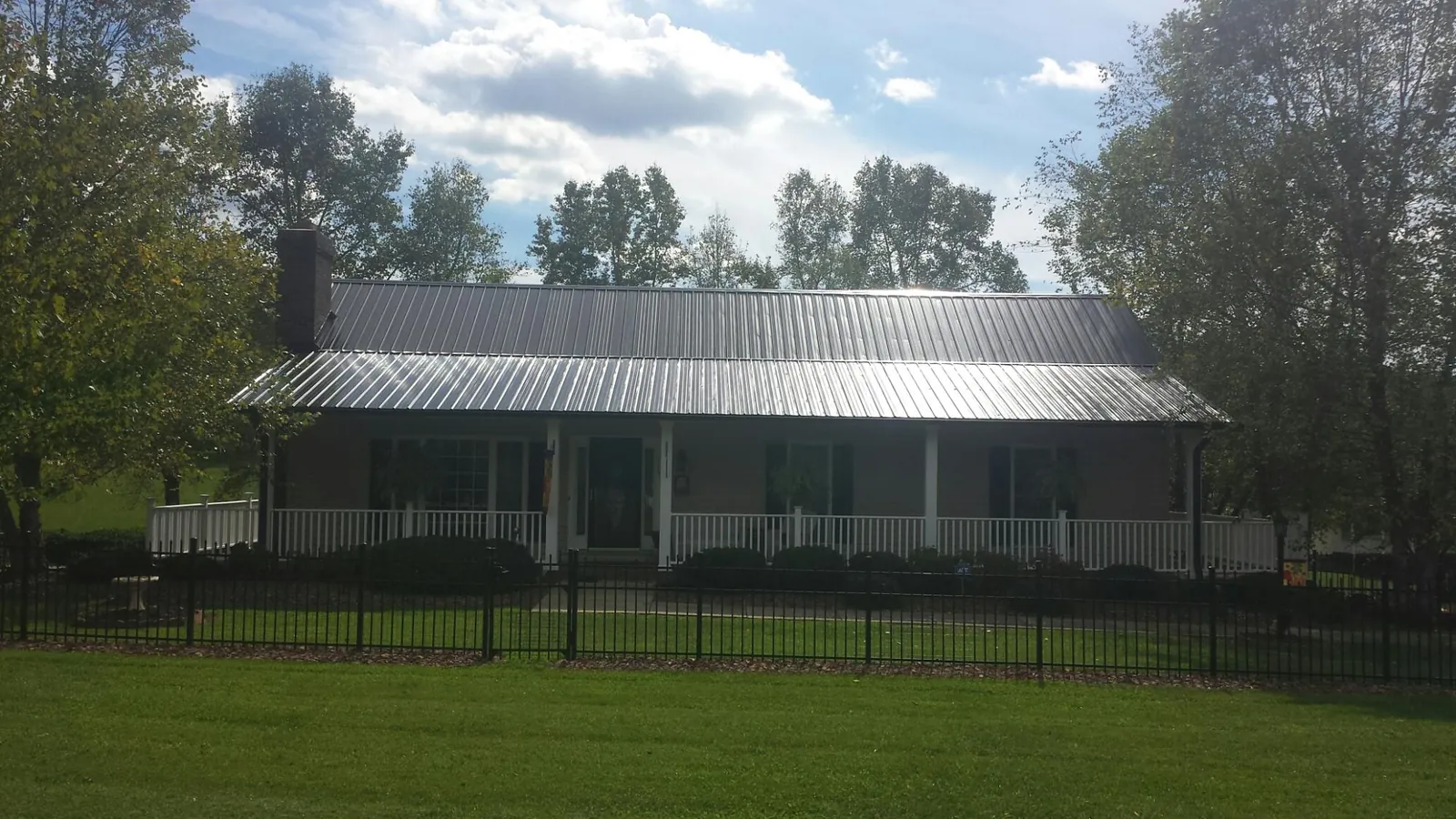 Gray metal roof on a brick ranch with a full width front porch — Gutter Guard Installation work by our crew in Springtown