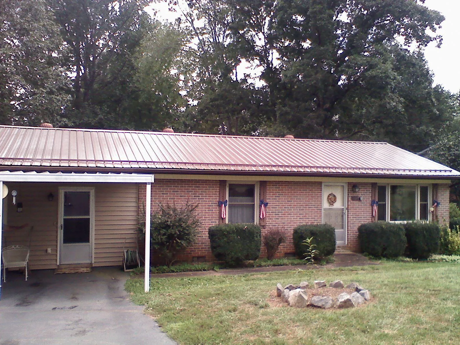 Bronze metal roof and carport on a brick ranch home — Roof Repair work by our crew in Springtown
